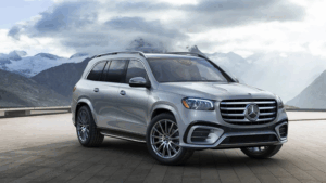 Front-side view of a silver Mercedes-Benz SUV parked on a mountaintop patio with misty peaks in background.
